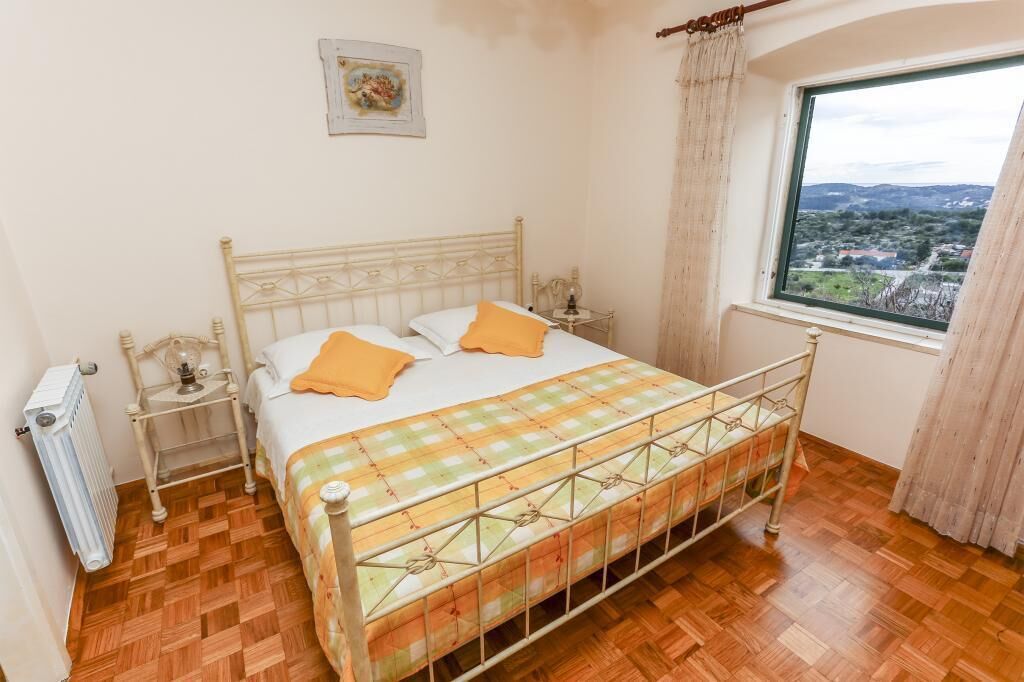 Un dormitorio con cama, un radiador, una ventana con vistas y una mesita de noche con lámpara.