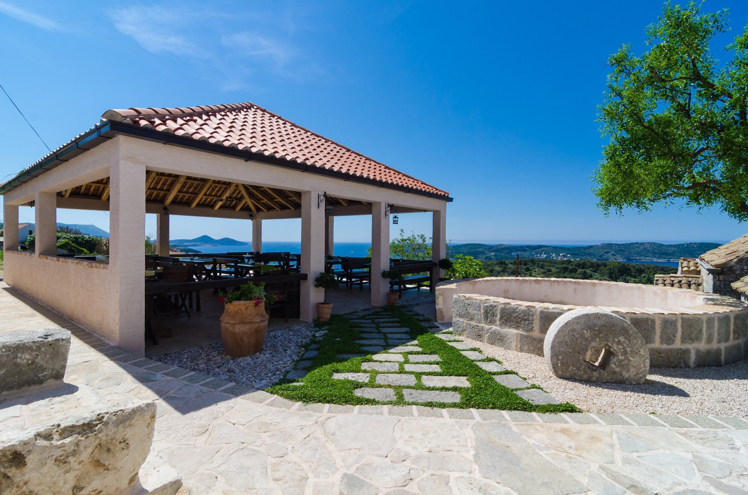 A covered outdoor seating area with stone flooring and a view of the landscape.