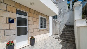 A modern apartment building with a stone facade, a glass door, and a staircase leading to an upper level. - Apartment Eulalija (Dubrovnik)
