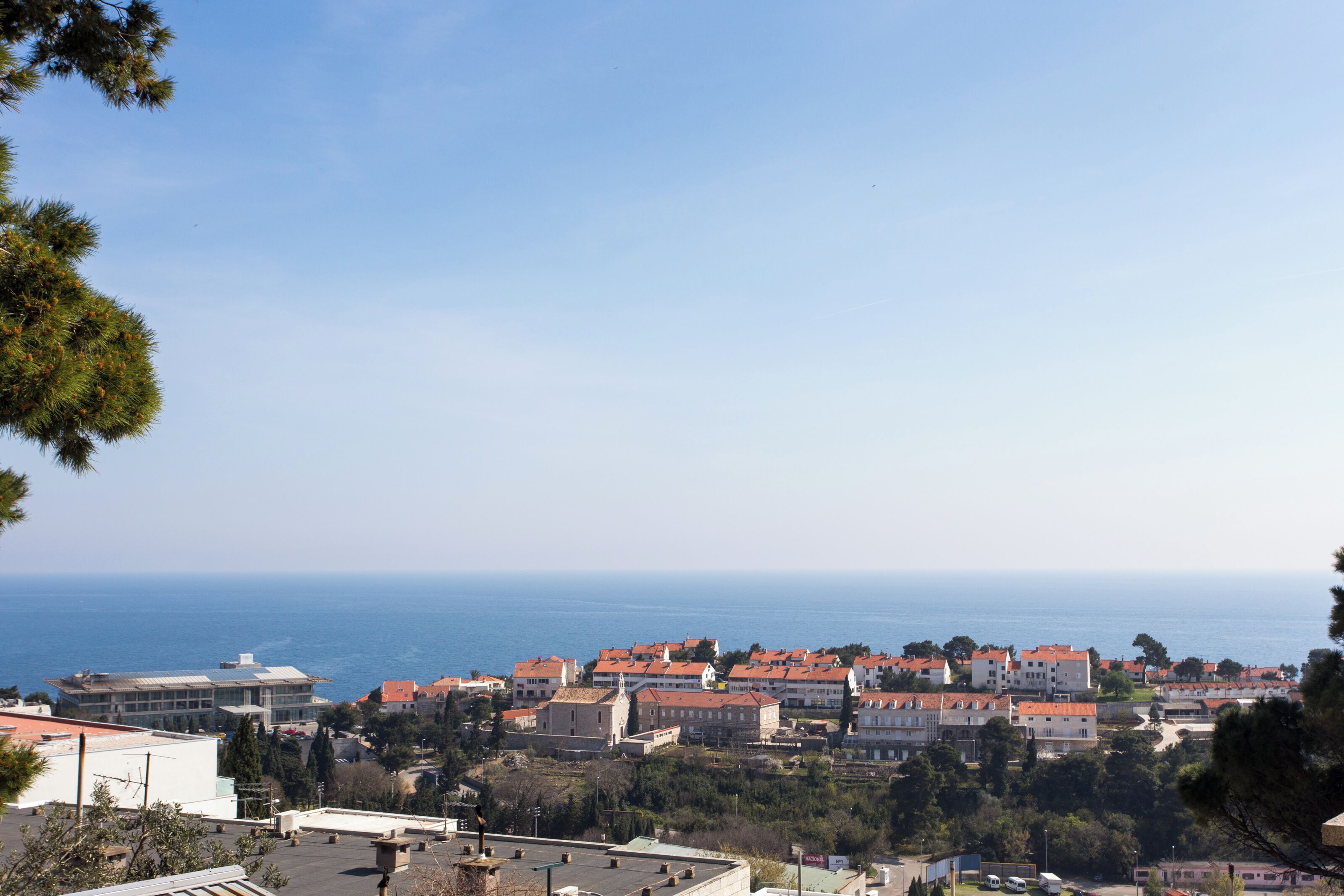 A coastal town with buildings, a clear sky, and the sea in the background.