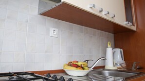 A kitchen with a gas stove, a sink, and a bowl of fruit. - Apartments Depozit-joky (Dubrovnik)