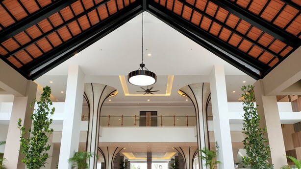 Eine großzügige Lobby mit hoher Decke, großen Kübelpflanzen und einem modernen Kronleuchter.