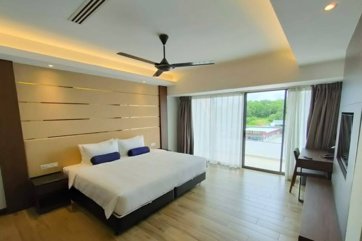 A modern hotel room with a large bed, a desk, and a view of the outdoors.
