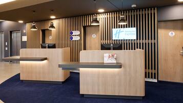 Un área de recepción con dos mostradores de madera, un cartel de Holiday Inn Express y una alfombra azul.