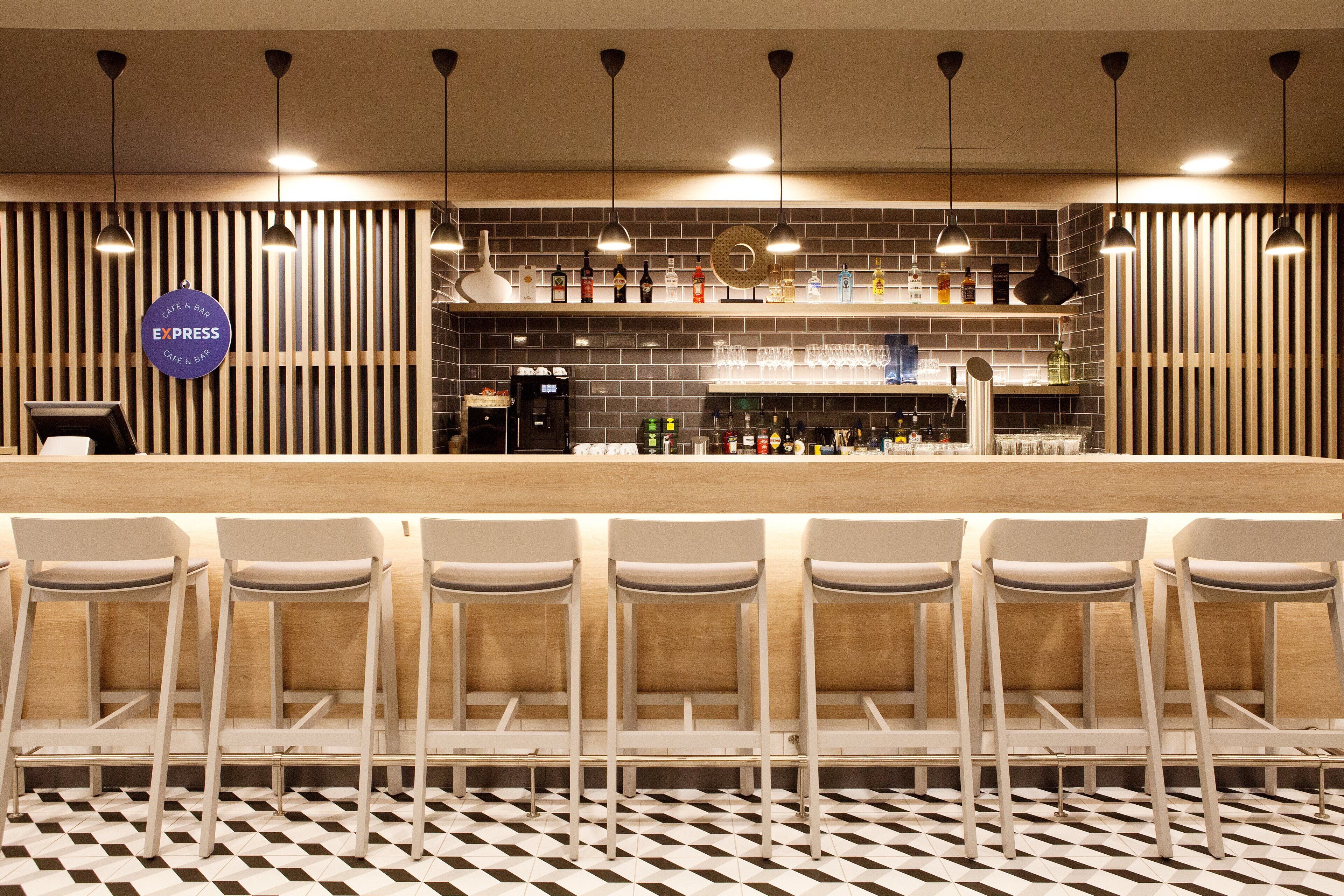 A bar area with a counter, bar stools, and a variety of bottles and glasses on shelves.