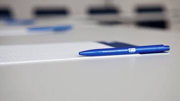 Ein blauer Stift auf einem weißen Notizblock mit liniertem Papier.