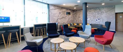 A modern lounge area with seating arrangements, a large window, and a map on the wall.