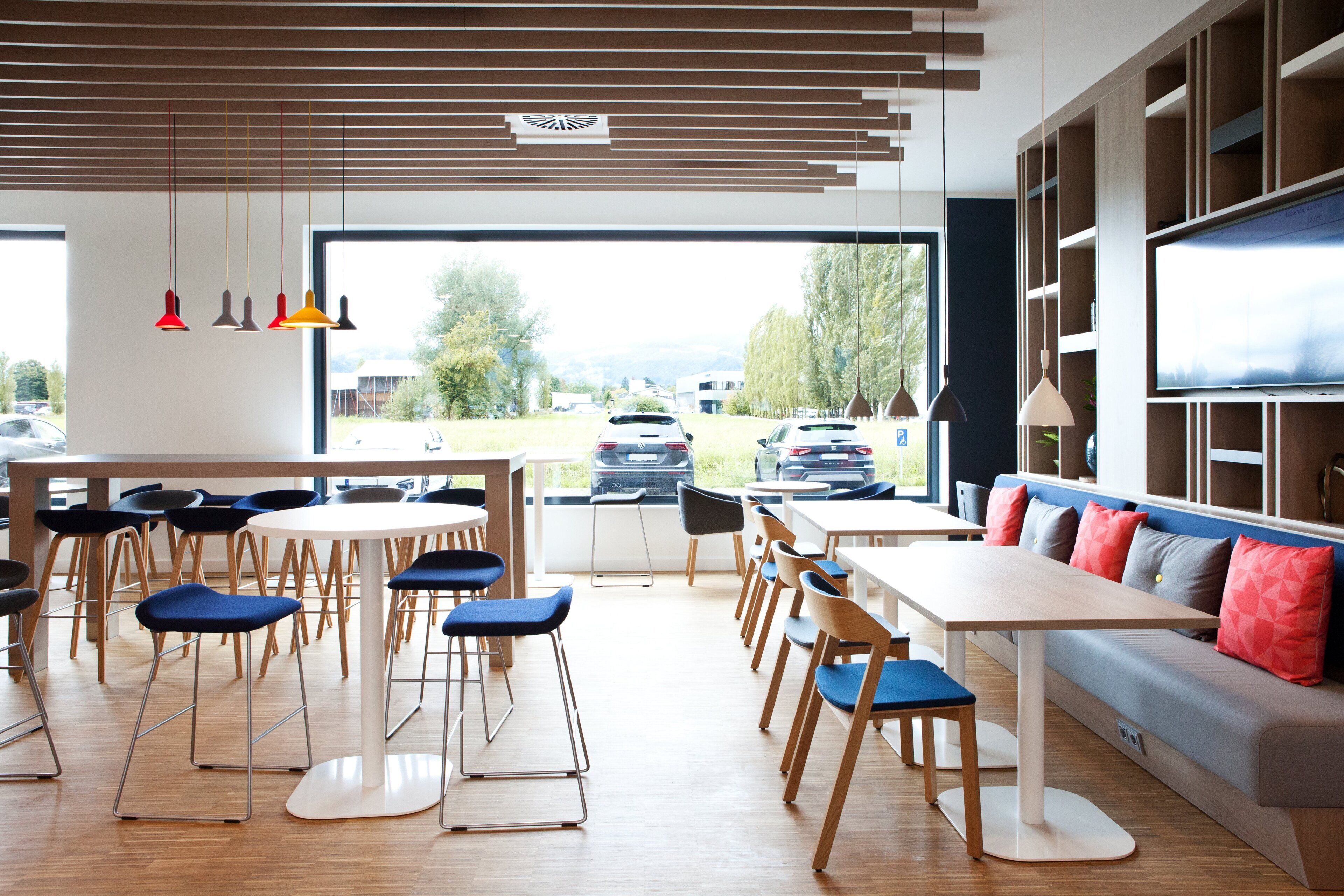 Een moderne eethoek met tafels, stoelen, een bank en een televisie.