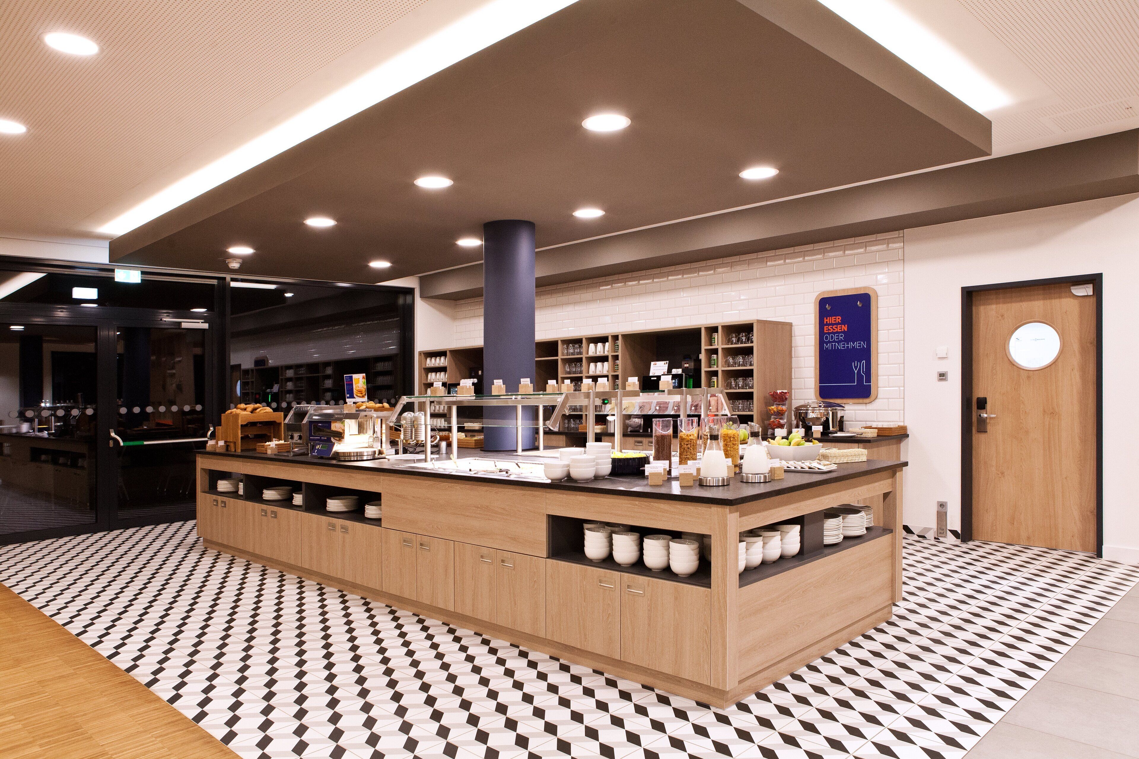 Un área de cocina moderna con una isla central, armarios de madera y piso de baldosas.