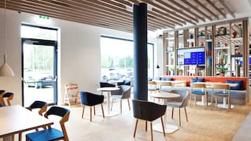 Un interno moderno con soffitto in legno, un'imponente colonna e una zona salotto con tavoli e sedie.