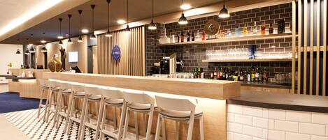 A modern bar area with a checkered floor, bar stools, and a variety of bottles and glasses on shelves.