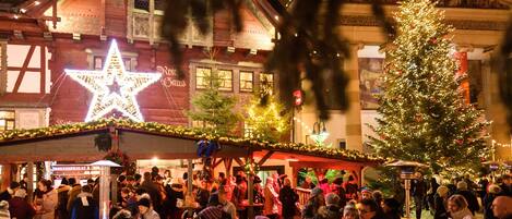 A crowded outdoor market with a large illuminated star and a decorated Christmas tree.