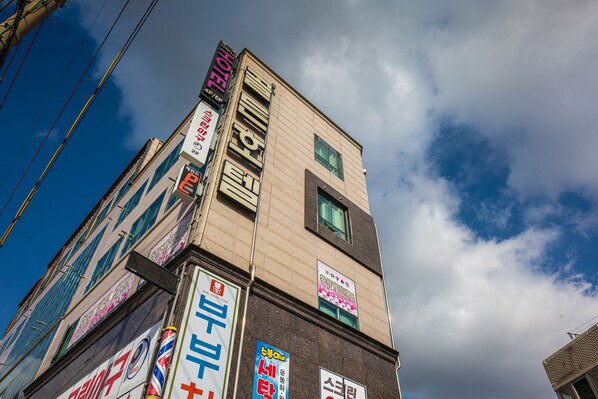 Un edificio de varios pisos con diferentes letreros, incluyendo un hotel y un letrero de estacionamiento.