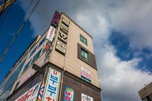 Un edificio de varios pisos con diferentes letreros, incluyendo un hotel y un letrero de estacionamiento.