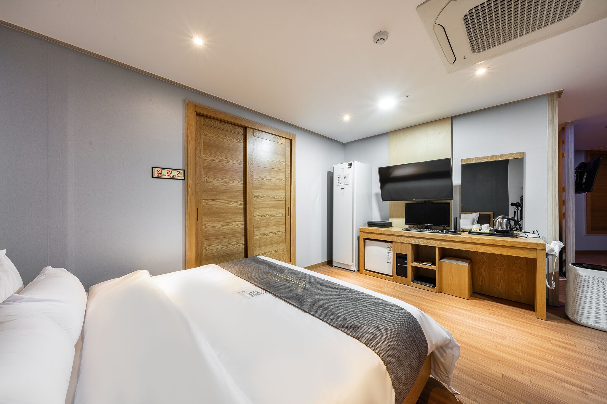 Ein Hotelzimmer mit Bett, Schreibtisch mit Computer, Kühlschrank und Fernseher.