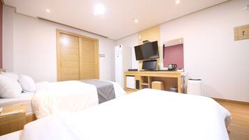 Ein Hotelzimmer mit zwei Betten, einem Schreibtisch mit Fernseher, einem Kühlschrank und einem Holzschrank.