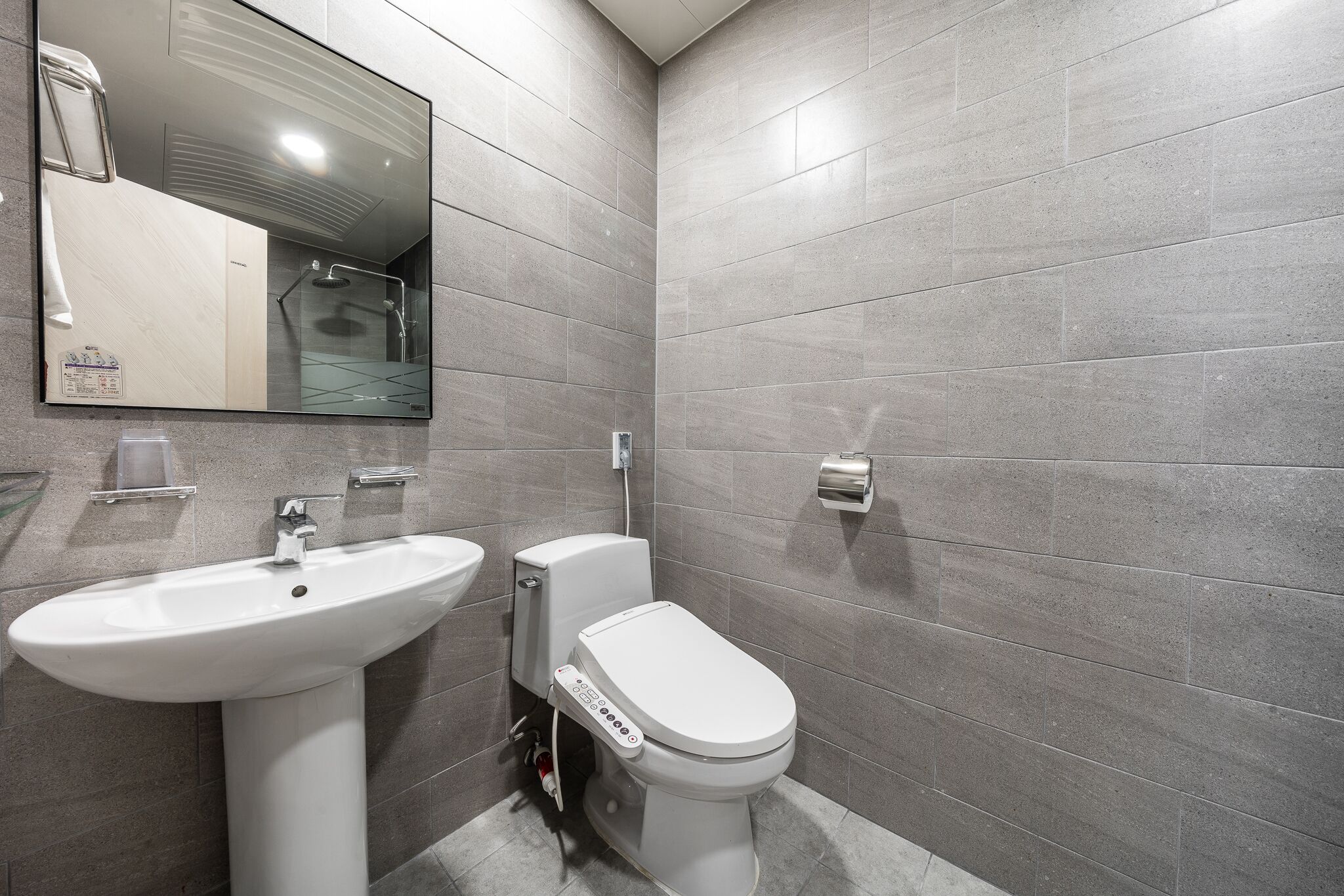 A modern bathroom with a white sink, toilet, and shower.