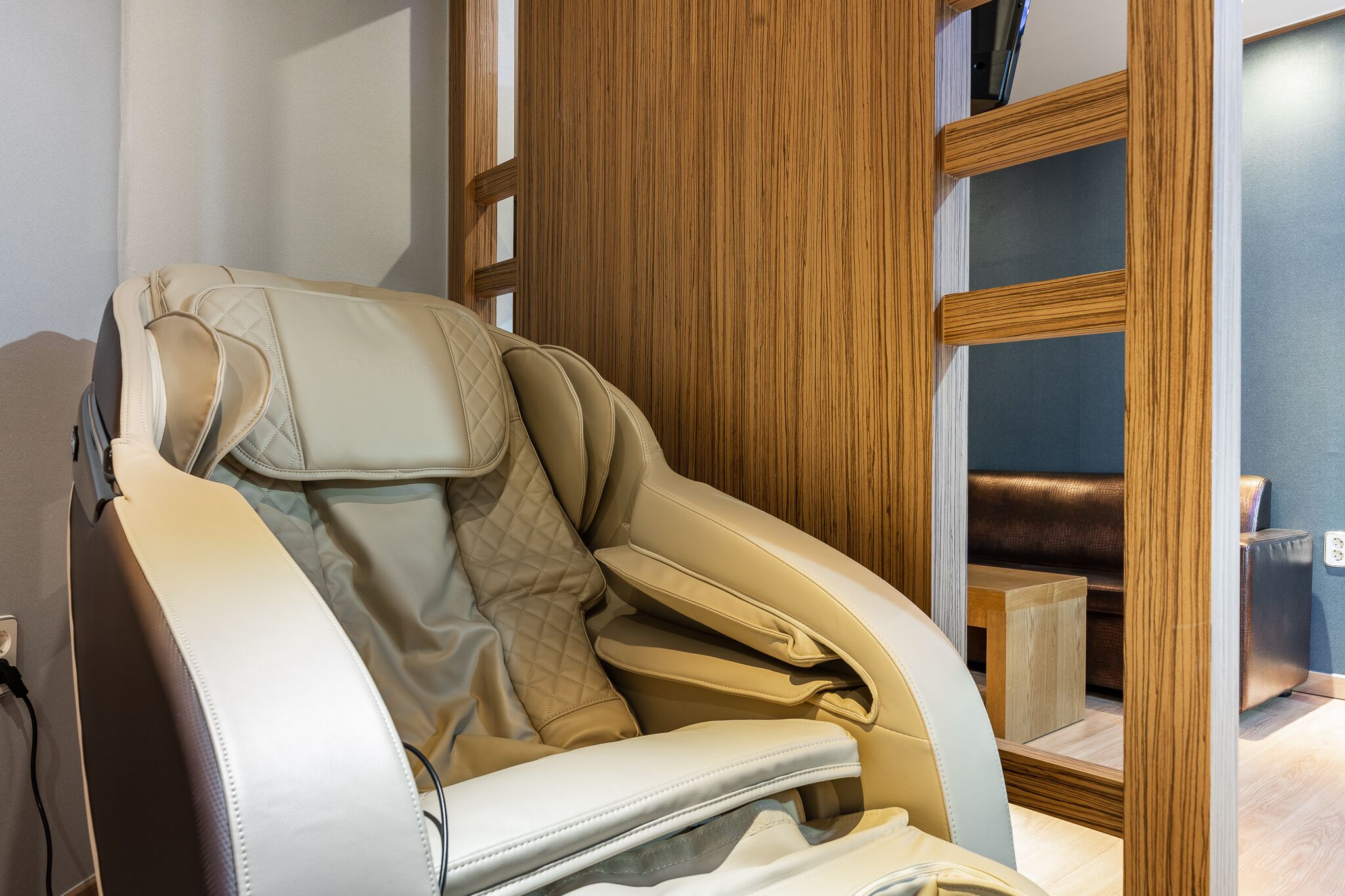 A massage chair in a room with wooden paneling and a small wooden table.