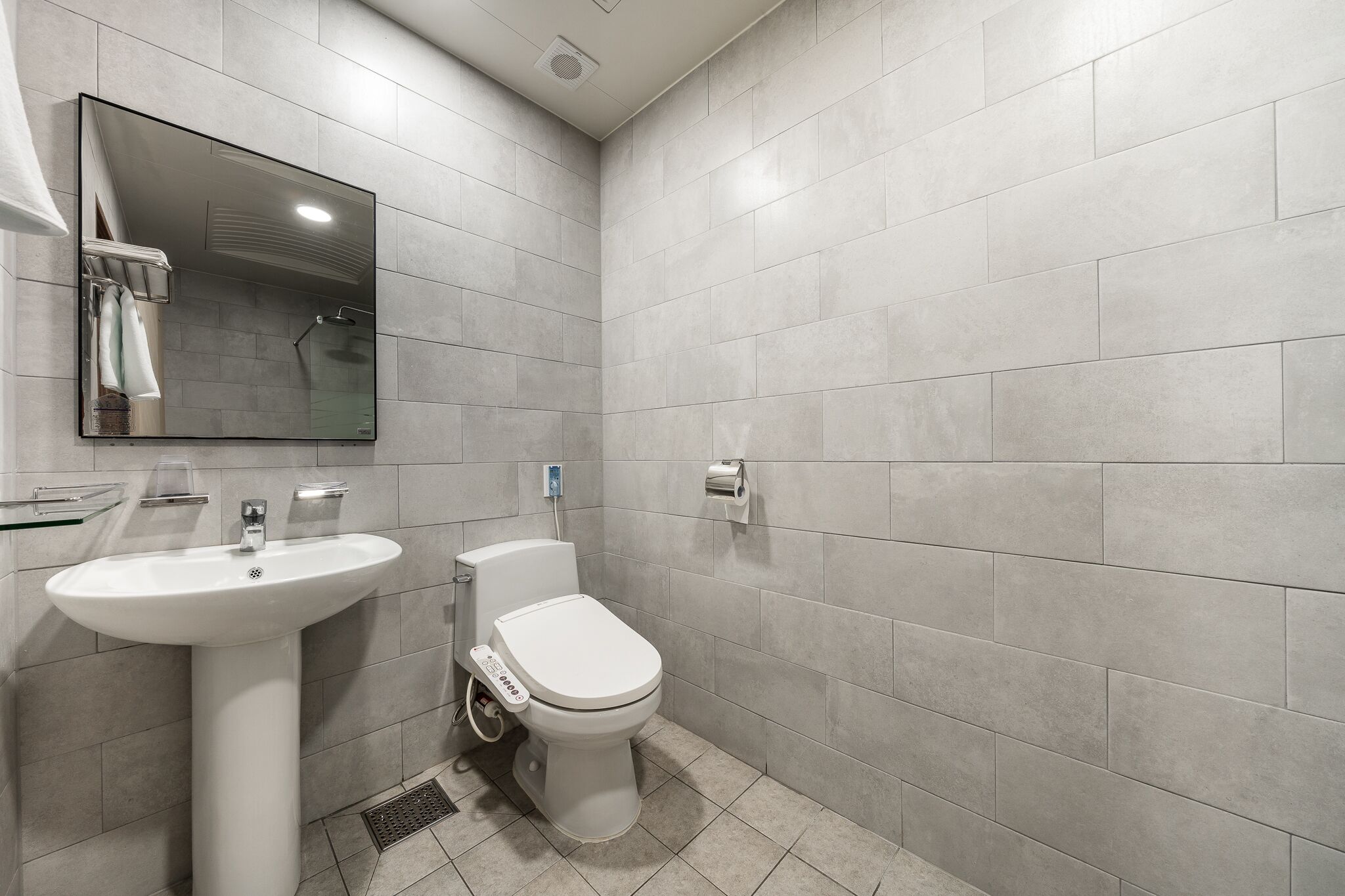 Un baño moderno con lavamanos, inodoro y ducha blancos.