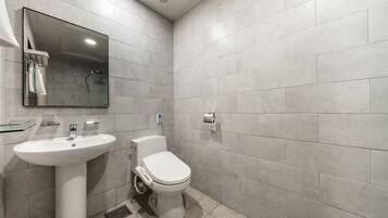 Un baño moderno con lavamanos, inodoro y ducha blancos.