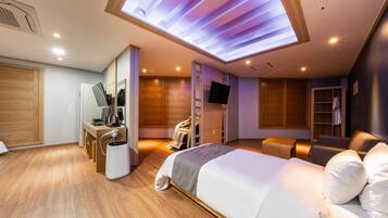 Een moderne hotelkamer met een groot bed, een bureau met een computer, een stoel, een kledingkast en een televisie.