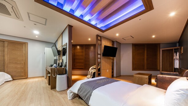 A modern hotel room with a large bed, a desk, a chair, and a TV mounted on the wall. - Golden Business Hotel (Seosan)
