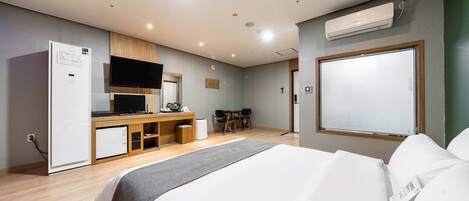 Ein modernes Hotelzimmer mit einem Bett, einem Schreibtisch, einem Fernseher und einer Klimaanlage.