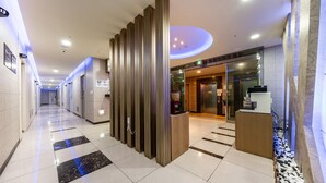 A hotel corridor with a modern design, featuring a reception desk, a glass door entrance, and a clean, tiled floor. - Golden Business Hotel (Seosan)