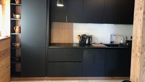 Una cocina moderna con armarios oscuros, encimera de madera y una lámpara colgante.