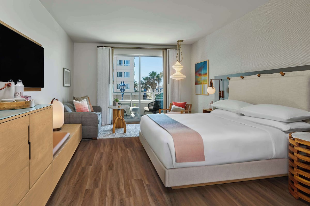 Un hotel moderno con una cama grande, un escritorio, un sofá y vistas de la ciudad.