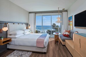 A modern hotel room with a large bed, a sofa, a TV, and a balcony with a view of the ocean. - MISSION PACIFIC BEACH RESORT, part of JdV by Hyatt (Oceanside)
