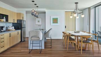 Una cocina moderna con armarios de madera, una isla central y una zona de comedor con mesa y sillas de madera.
