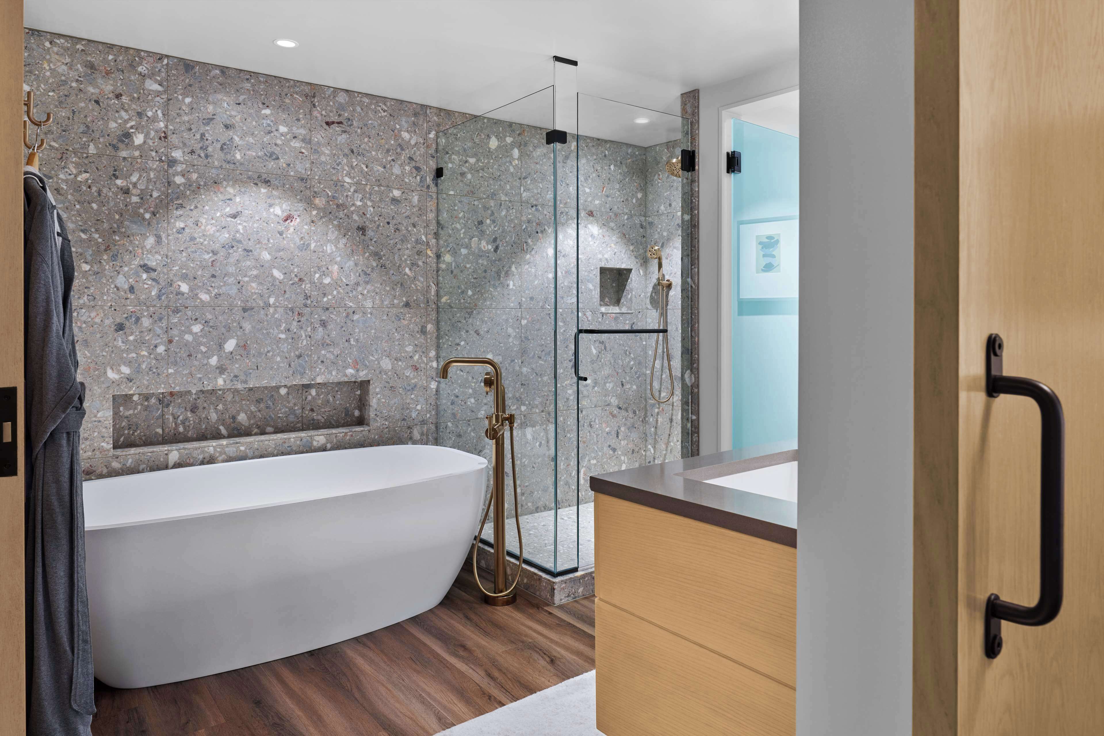 A modern bathroom with a freestanding bathtub, a glass-enclosed shower, and a wooden vanity.