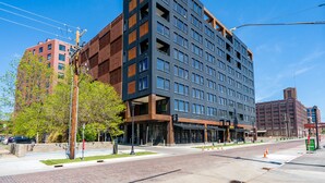A modern multi-story hotel with a mix of glass and brick facades, large windows, and a visible entrance with a sign.