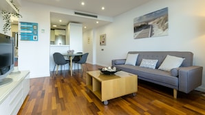 Un salon moderne avec un canapé gris, une table basse en bois et un téléviseur à écran plat.