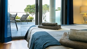 Une chambre à coucher avec un lit, une vue sur l’extérieur et un balcon équipé de chaises.