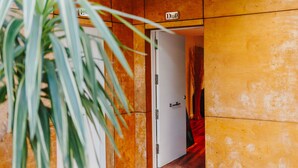 Une chambre d’hôtel avec un mur en bois, une porte blanche et une plante au premier plan.