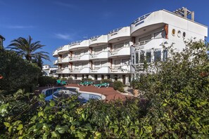 A modern hotel with multiple balconies, a swimming pool, and lush greenery. - V005 - Cargols de Mar 5, Casa en residencia privada con piscina delante de la playa. (Empuriabrava)