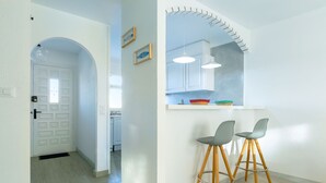 A modern kitchen with white cabinets, two bar stools, and pendant lights. - V005 - Cargols de Mar 5, Casa en residencia privada con piscina delante de la playa. (Empuriabrava)