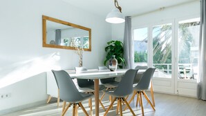 A dining area with a white table, grey chairs, and a wooden floor. - V005 - Cargols de Mar 5, Casa en residencia privada con piscina delante de la playa. (Empuriabrava)