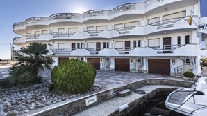 A multi-story building with balconies, a private label, and a marina with boats. - V005 - Cargols de Mar 5, Casa en residencia privada con piscina delante de la playa. (Empuriabrava)