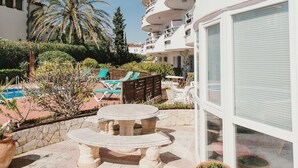 Ein Innenhof eines Resorts mit Pool, Liegestühlen und Essbereich.