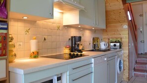 A compact kitchen with a gas stove, coffee maker, and a washing machine.