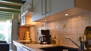 A kitchen with white cabinets, a coffee maker, a kettle, and a sink.