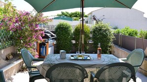 An outdoor patio with a table, chairs, and a large umbrella.