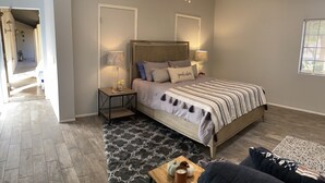 Una camera da letto con un letto, comodini, una ventola a soffitto e una finestra con persiane.