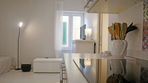A hotel room with a bed, bedside table, lamp, and a view of the outside. - CASA ADRIA (Alghero)