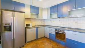 A kitchen with blue cabinets, a stainless steel refrigerator, a microwave, and an oven. - Apartment Sun & Sky (Dubrovnik)