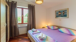 A bedroom with a bed, curtains, a painting, and a window. - Apartment Sun & Sky (Dubrovnik)