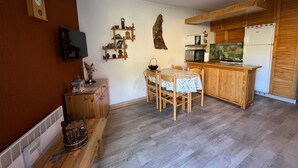 A compact kitchen with a dining area, wooden cabinets, a microwave, and a television. - 28m² Studio at the slopes base, 4 pax, Les Cimes residence (Enchastrayes)